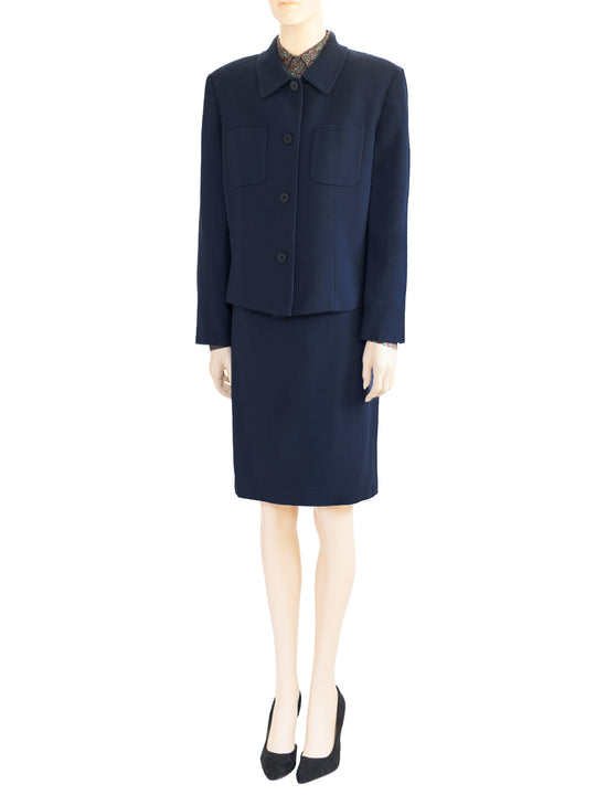 The model wears Chaus's vintage dark blue two-piece wool skirt suit from the 1980s. Boxy style jacket, padded shoulders.